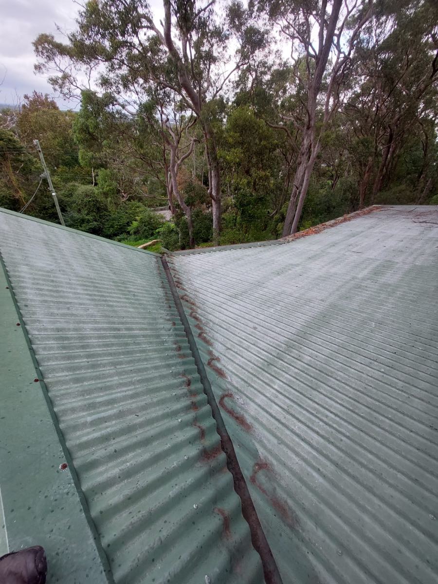 Roof valley with debris build-up and rust staining before gutter guard