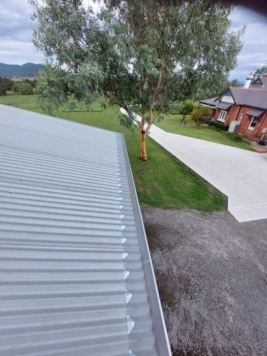 Long metal roof gutter run cleared, with the house and driveway below
