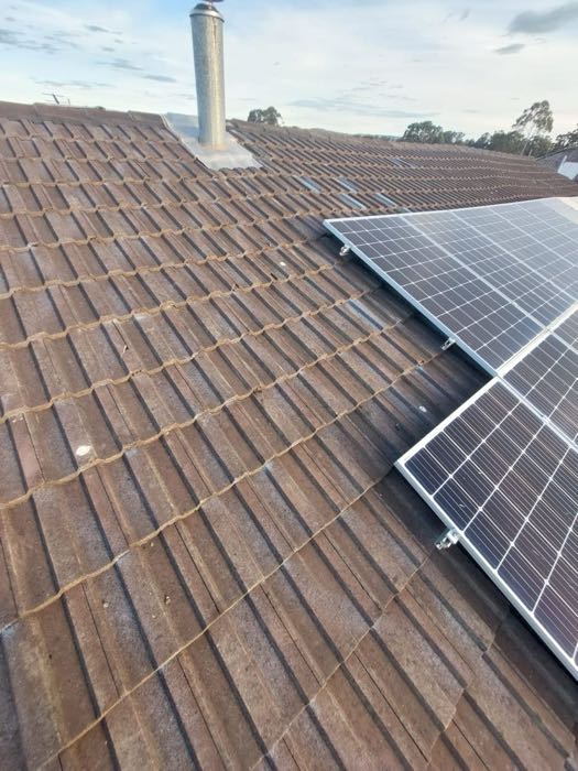 Repaired tile roof beside a solar array